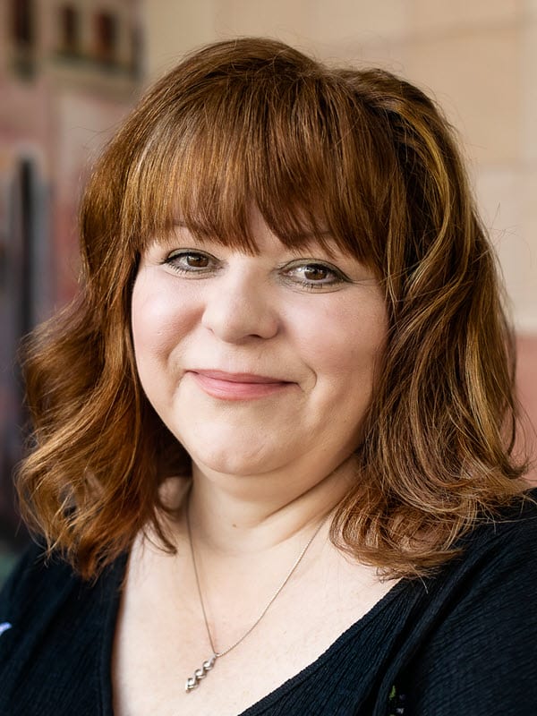 Lisa Rivera Director of Development wearing a black top and a necklace.