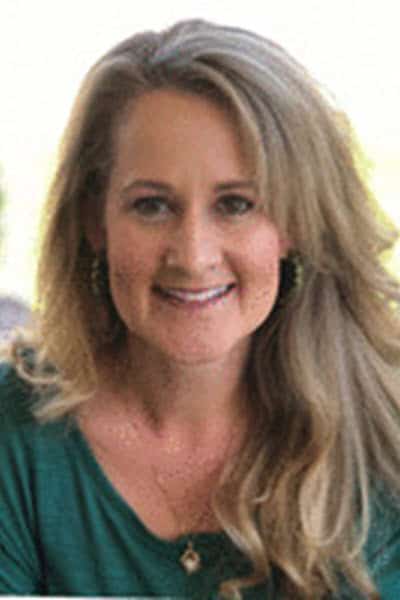 A woman in a green shirt smiles for the camera.